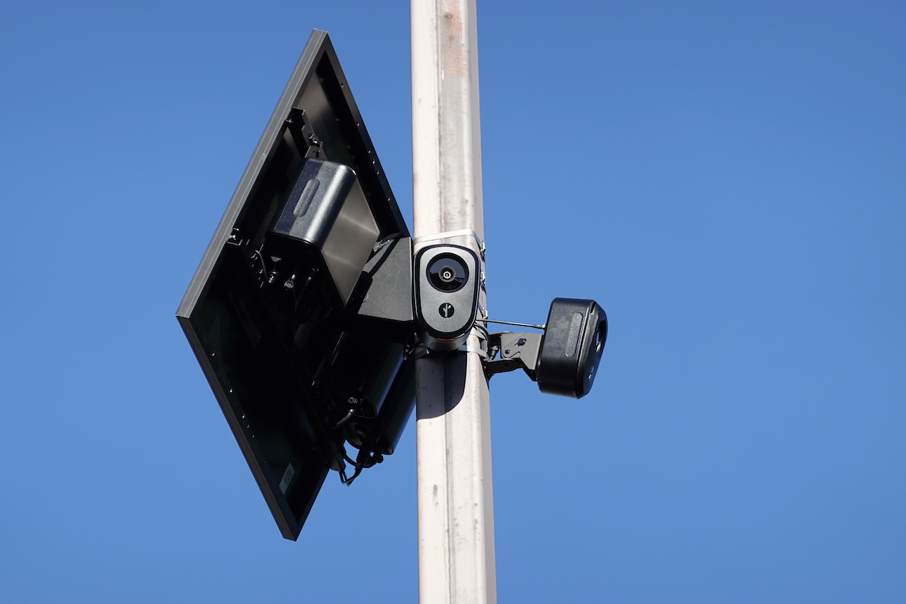 Two Flock cameras and a solar panel on a light pole.